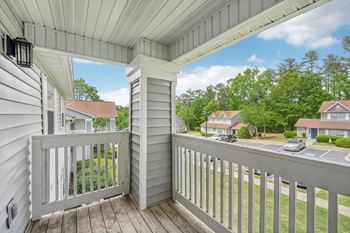 A view from a porch looking out at a parking lot and other houses.